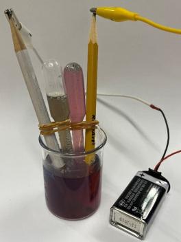 Setup for the electrodes and gas collection pipets.  Each pipette/pencil assembly was placed in a 50 mL beaker filled about halfway with electrolyte and pea flower tea solution. The other end of each sharpened pencil was connected by clips to a 9 V battery.