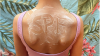 Top of a female's back, wearing swimsuit with letters 'SPF' written in sunscreen on skin